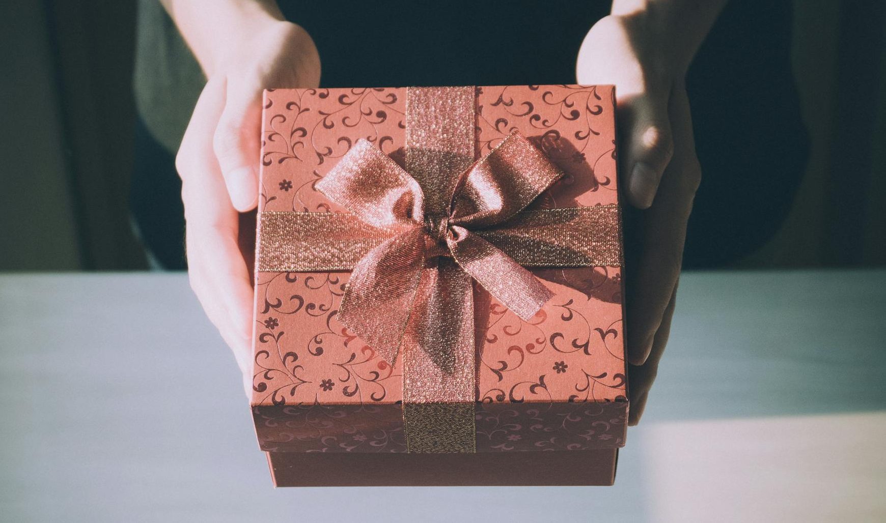 C'est un paquet cadeau rouge avec un noeud tenu entre des mains